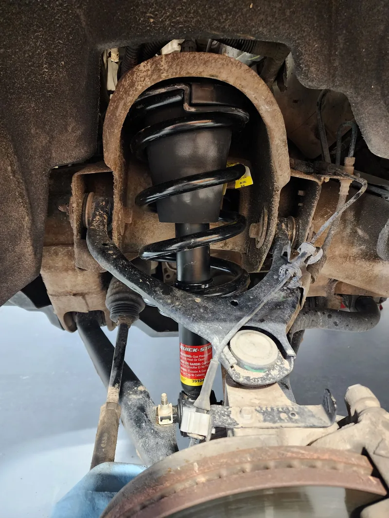 Newly fitted coil spring and strut seen from under a raised vehicle