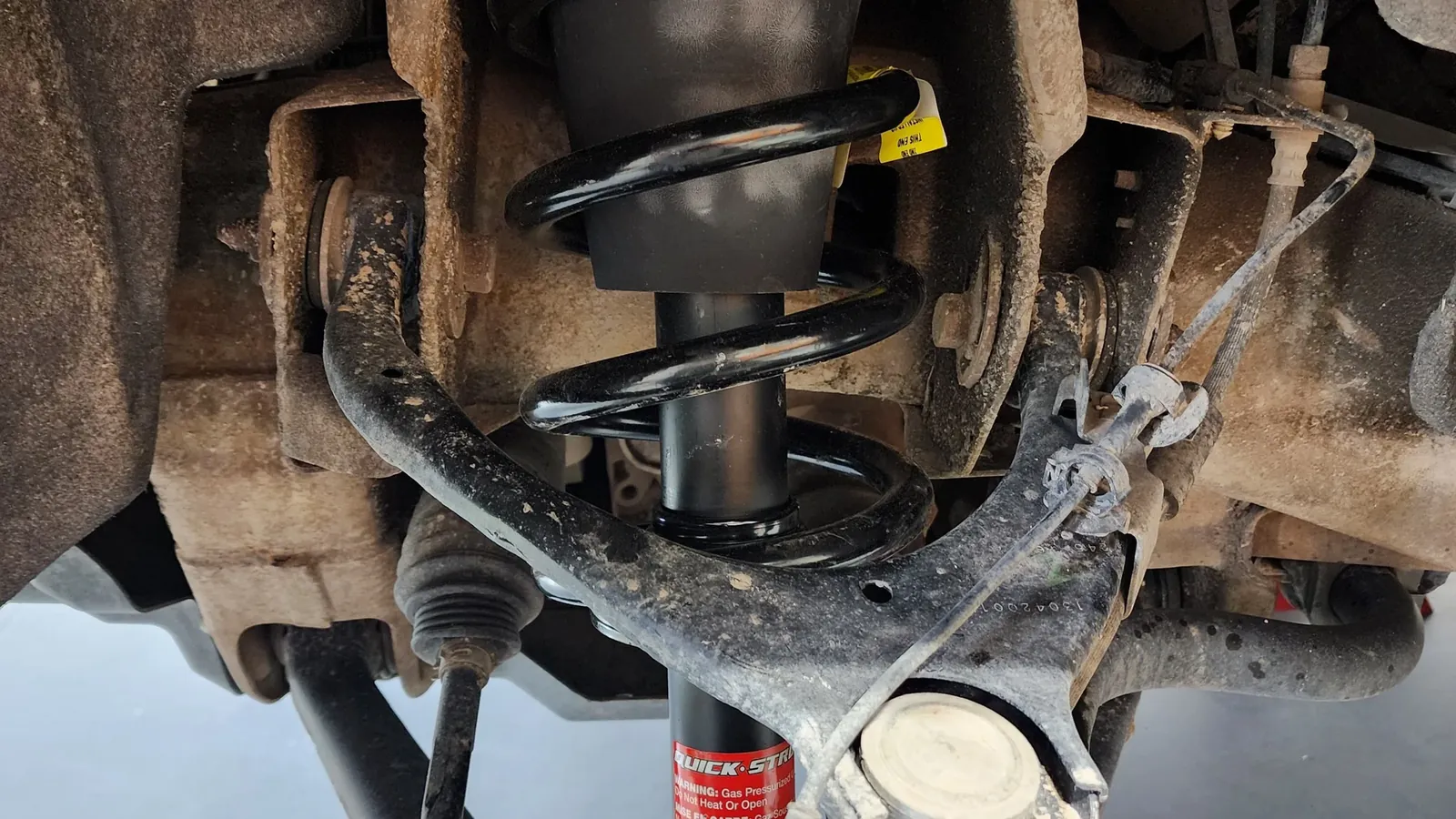 Newly fitted coil spring and strut seen from under a raised vehicle