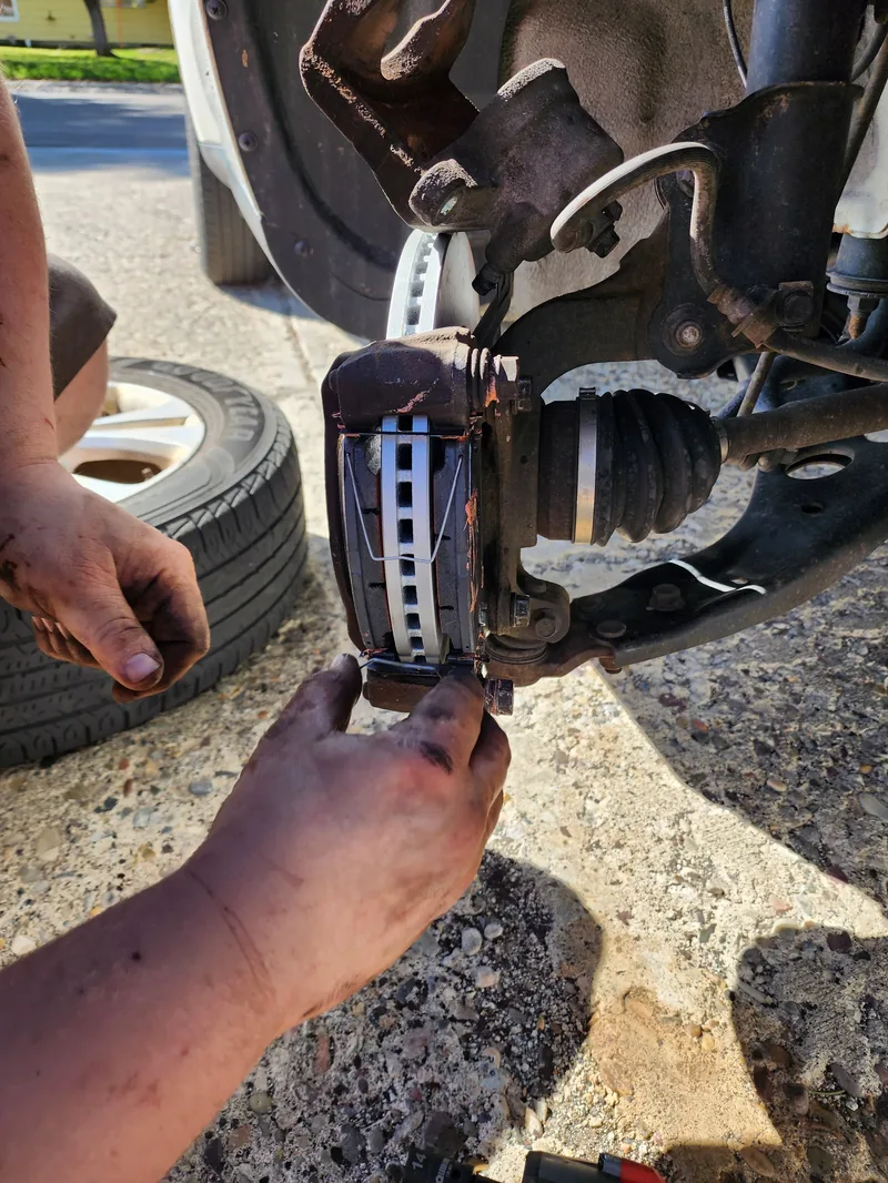 Mobile mechanic fitting a CV axle boot and brake components at the roadside