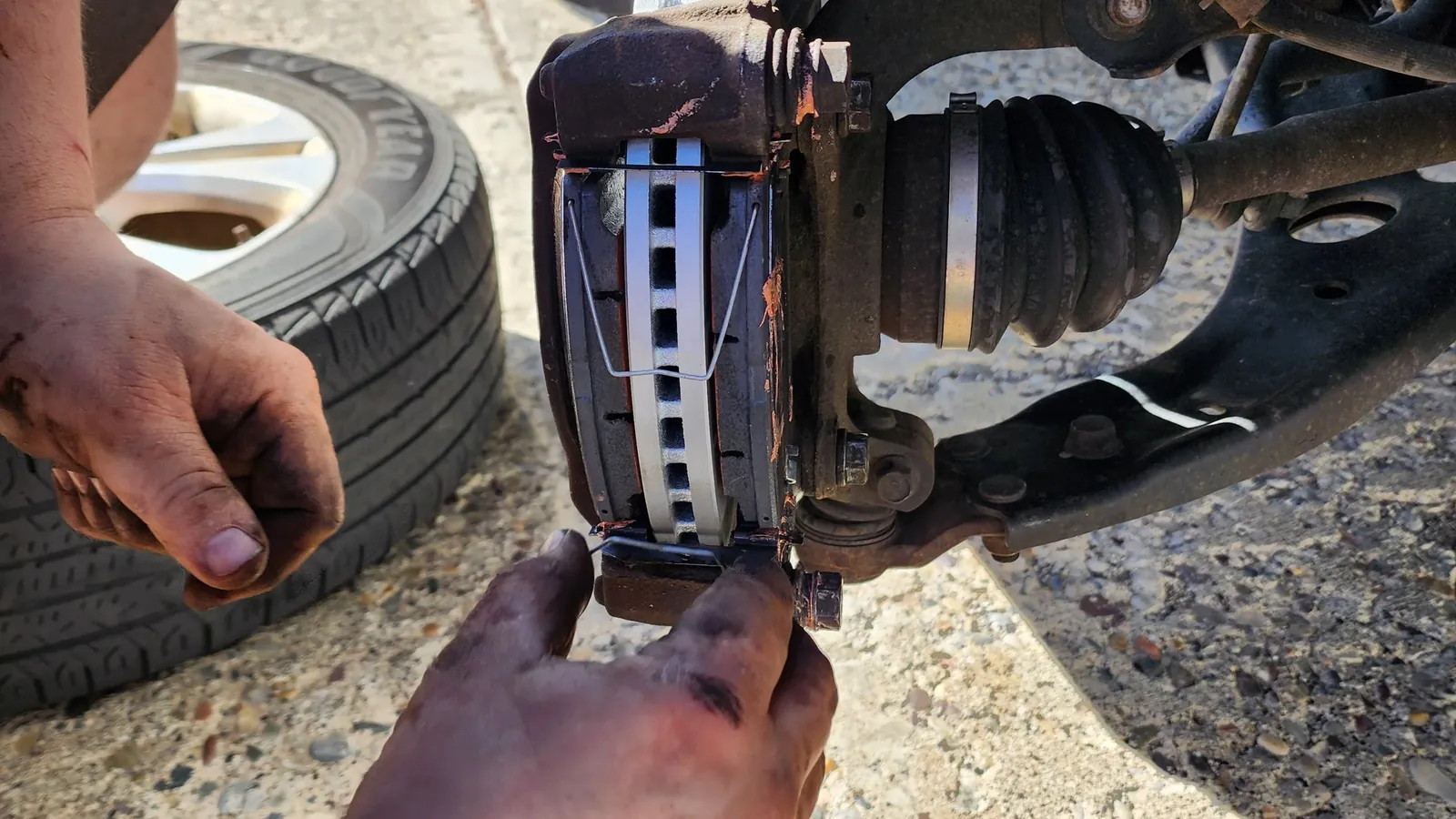 Mobile mechanic fitting a CV axle boot and brake components at the roadside