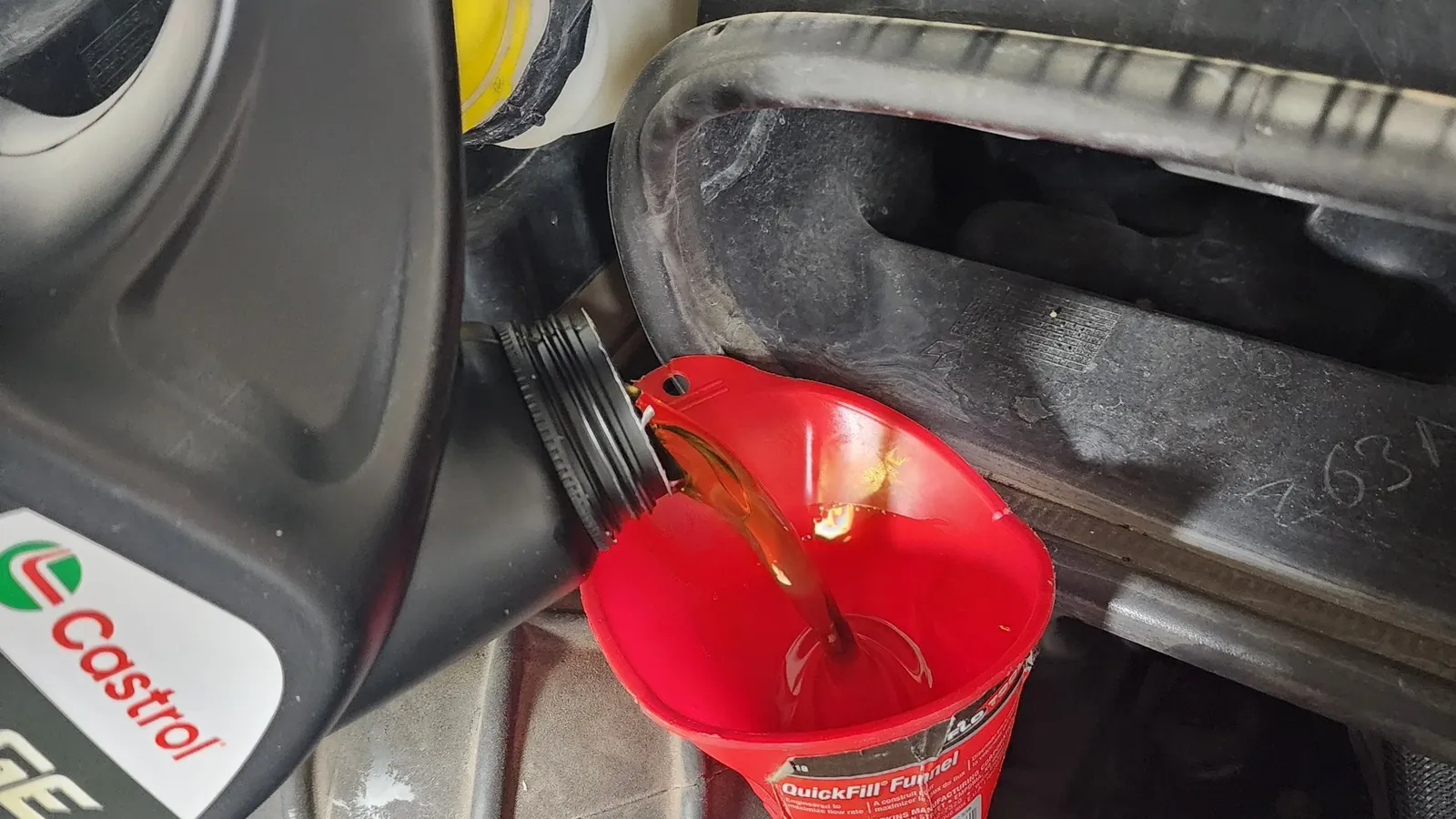 Fresh engine oil being poured through a funnel during a mobile oil change
